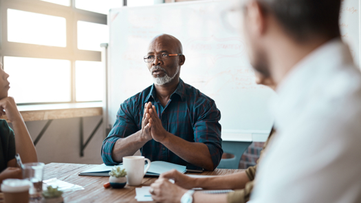 A black male social worker (or other professional) addressing a meeting around a table