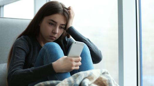 A young girl looking down or shamed while looking at her phone